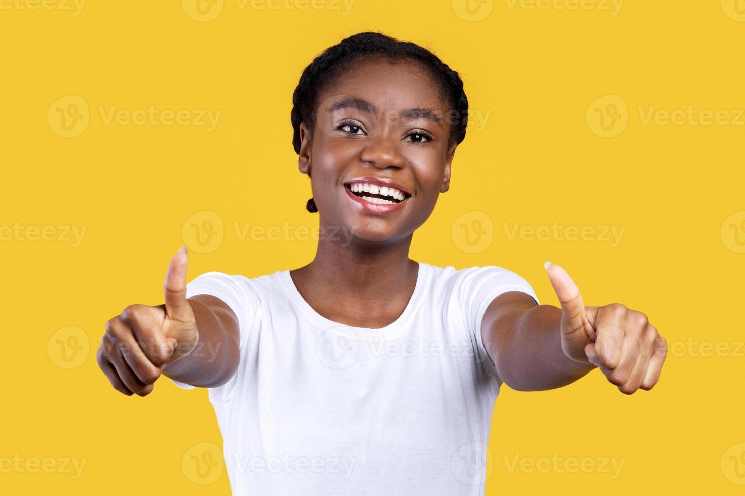 I Like It. Smiling African Woman Gesturing Thumbs Up With Both Hands Smiling To Camera Posing On Yellow Studio Background. Young Black Lady Showing Thumbs Approving And Advertising Something photo