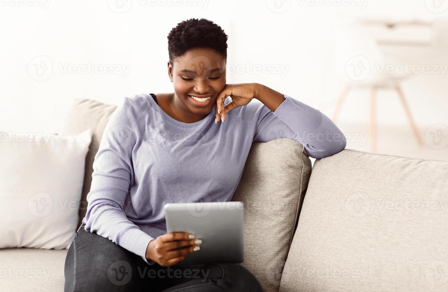 Technology. Portrait Of Smiling African American Woman Using Digital Tablet, Watching Movie Or , Enjoying Free Time. Young Lady Sitting On The Sofa With Gadget, Cheking Email photo