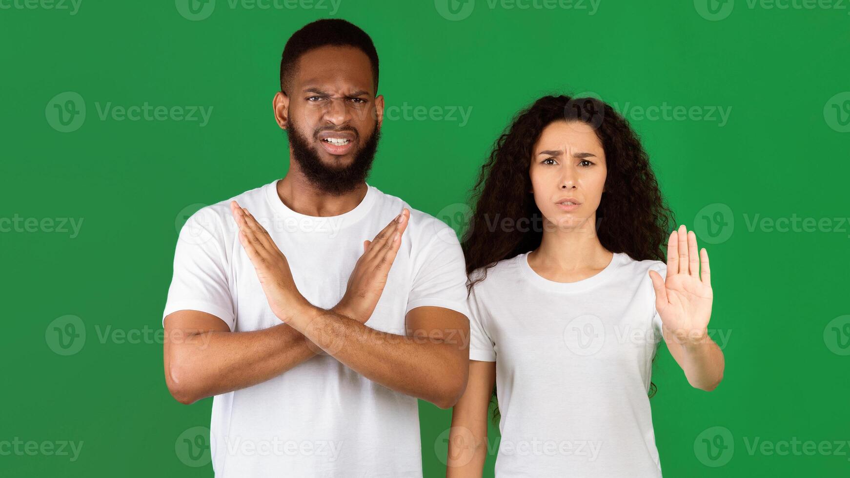 Don't Do It. Multiethnic Woman And Man Gesturing Stop And Crossing Hands Forbidding And Disapproving Something Standing On Green Studio Background. Restriction, Warning Concept. Panorama photo