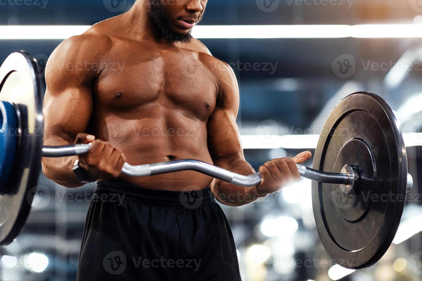 Closeup of muscular african american bodybuilder exercising with heavy barbell at gym, copy space. Athletic black man making weightlifting or powerlifting, working on arms and chest musculs photo
