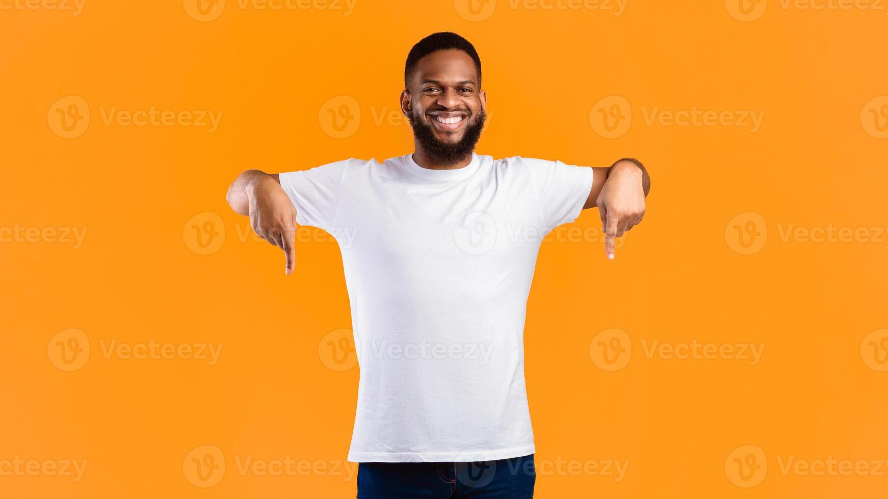 African American Guy Pointing Fingers Down Advertising Something Standing Posing In Studio Over Yellow Background, Smiling To Camera. Advertisement Banner, Look There Concept. Panorama photo