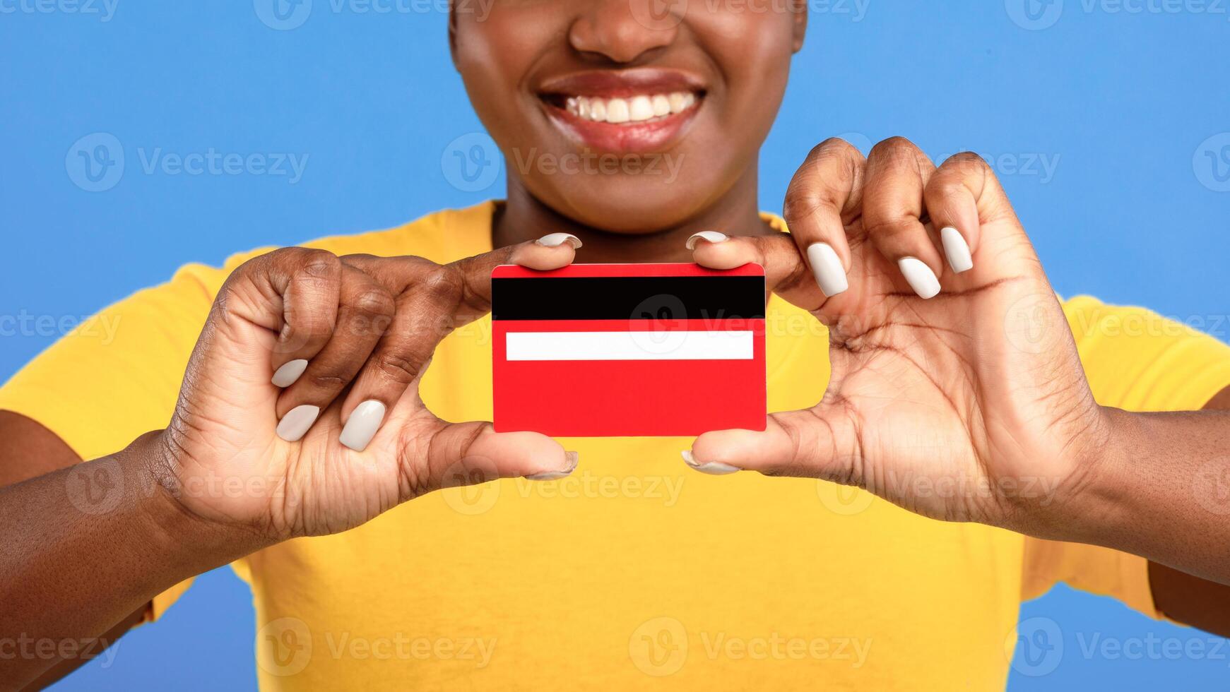 Cheerful Black Lady Showing Credit Card To Camera Advertising Bank Service Posing Over Blue Background, Studio Shot. Financial Advertisement, Banking, Money And Finance Concept. Selective Focus photo