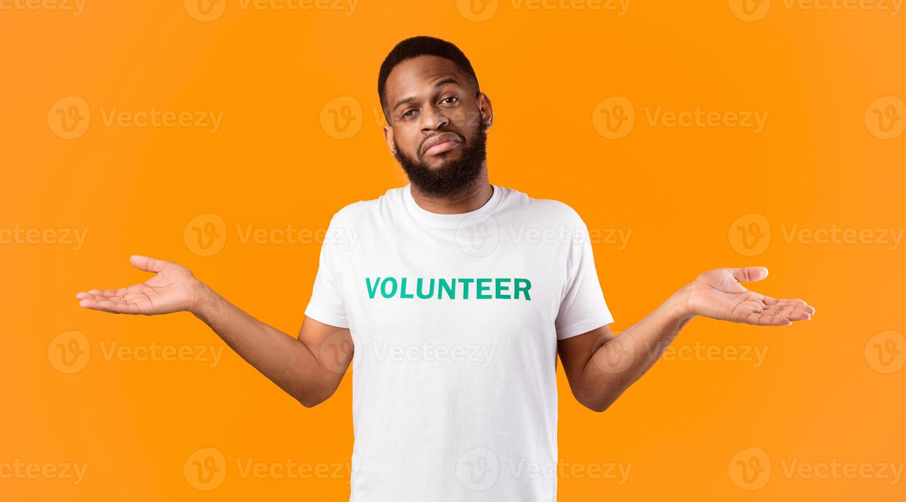 African American Male Volunteer Shrugging Shoulders Looking At Camera Posing In Studio Over Yellow Background. Portrait Of Indifferent Activist Guy Concept. Who Cares Concept photo