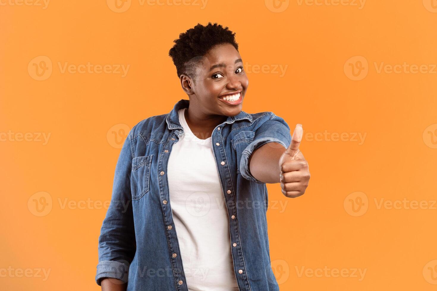 Cheerful Overweight African American Lady Gesturing Thumbs Up To Camera Approving Something Posing Standing On Yellow Studio Background. I Like It, Thumbs-Up Gesture Concept photo