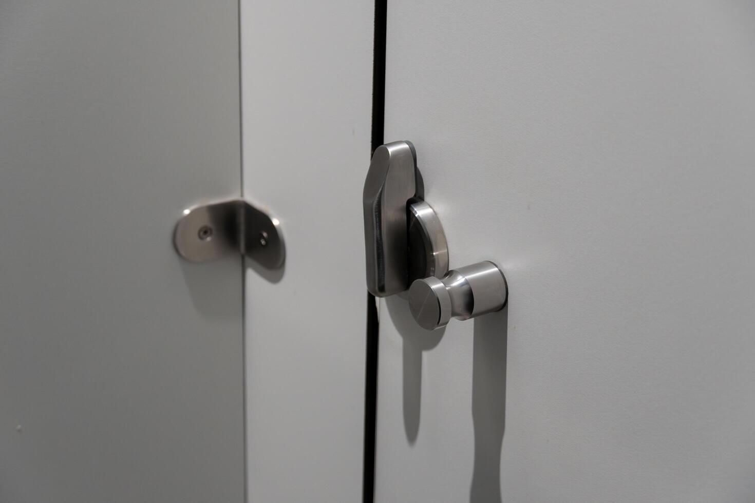 A pair of sleek stainless steel locks are fastened to a white cabinet door, highlighting the modern design elements of the interior space photo