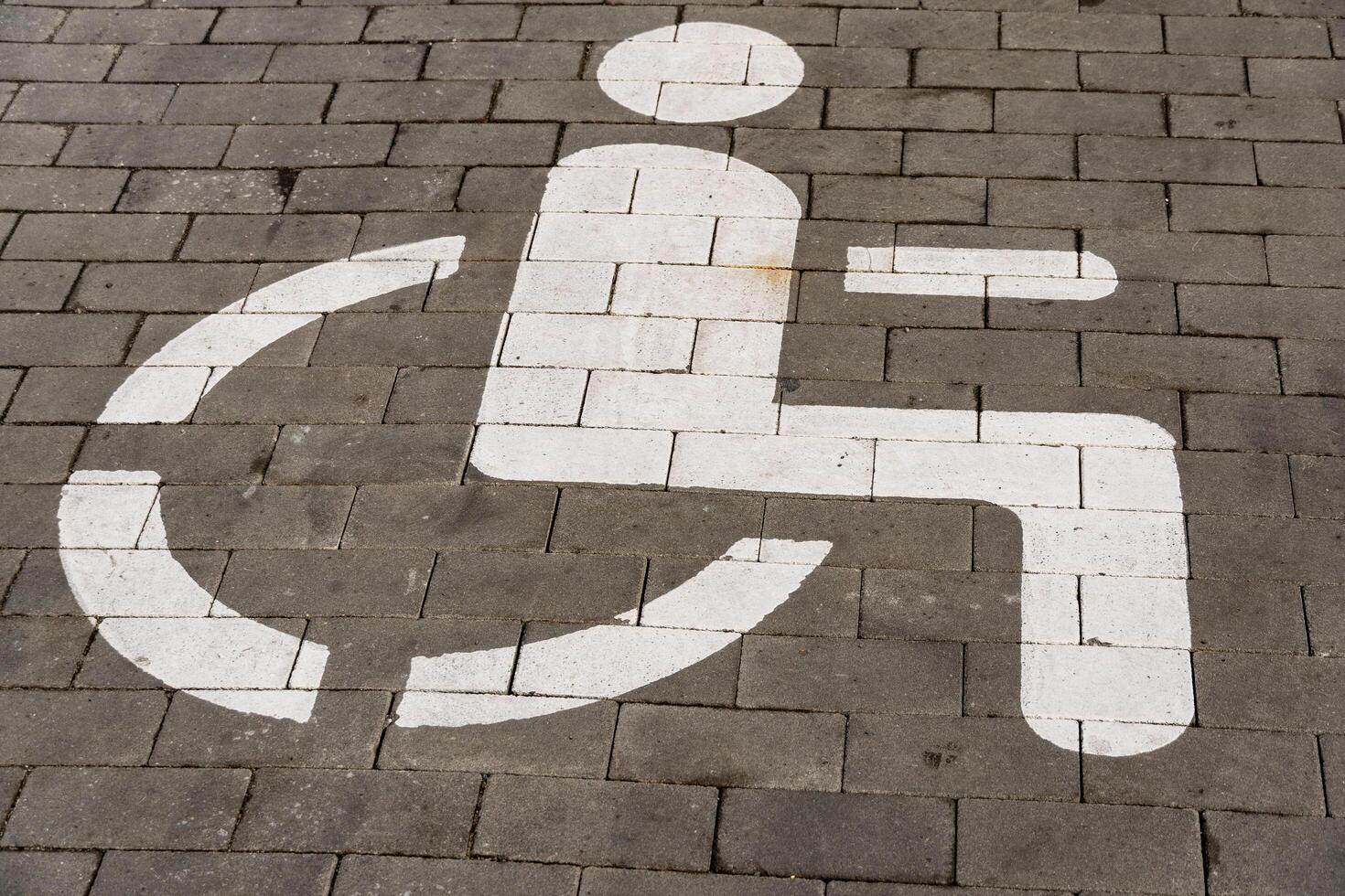 Pavement features a clear white symbol indicating a designated parking space for individuals with disabilities photo