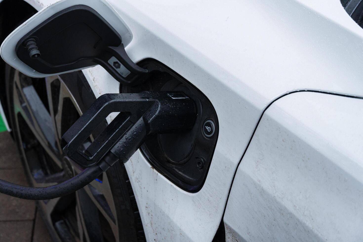 An electric car is being charged at a public station, showcasing the innovative design of the vehicle's power connection photo