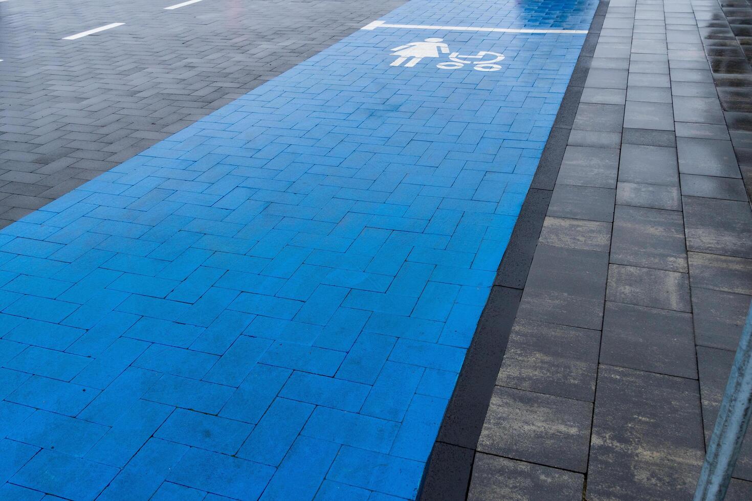 A newly developed blue lane designed for pedestrians and cyclists runs alongside a paved road, enhancing safety and promoting alternative transportation in a city environment photo