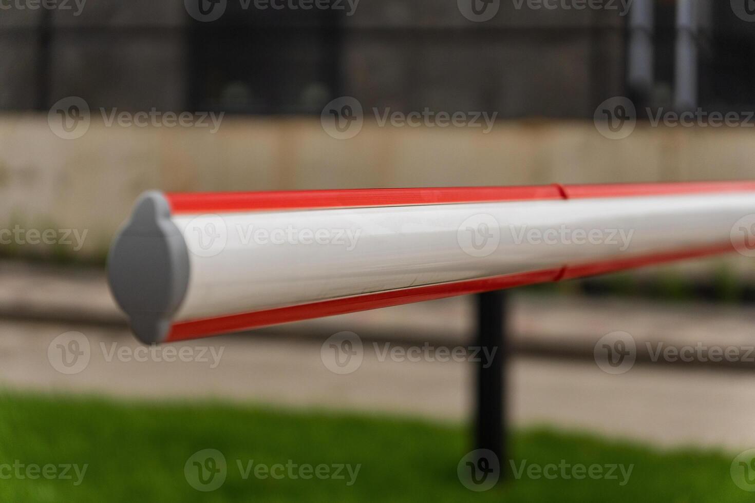 A red and white barrier gate stands firmly at the entrance of a parking lot, creating a clear boundary. The gate emphasizes security and control, enhancing safety for vehicles and pedestrians photo