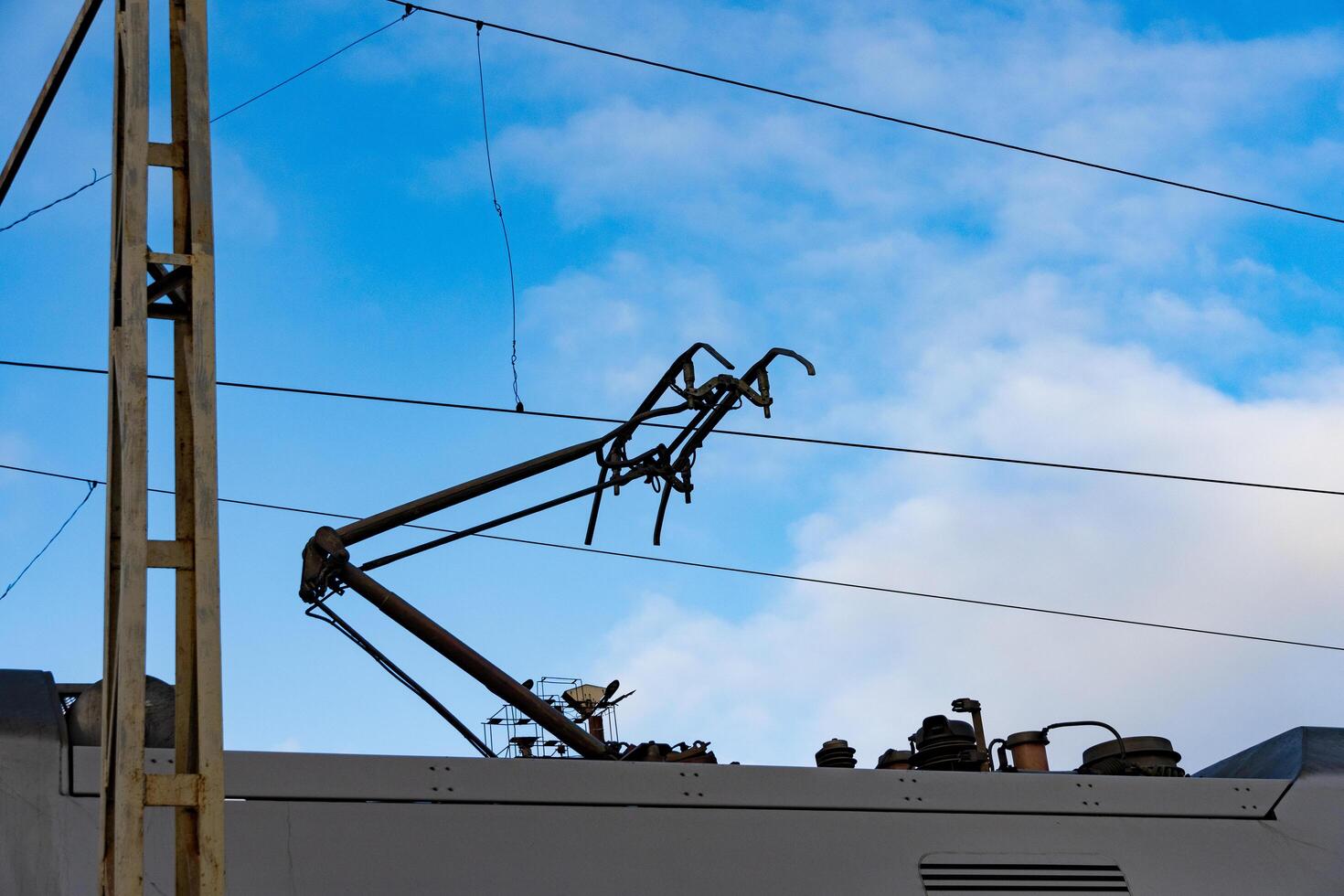 Electric train components are visible against a vibrant blue sky, showcasing the intricate design of modern railway systems and their essential infrastructure photo