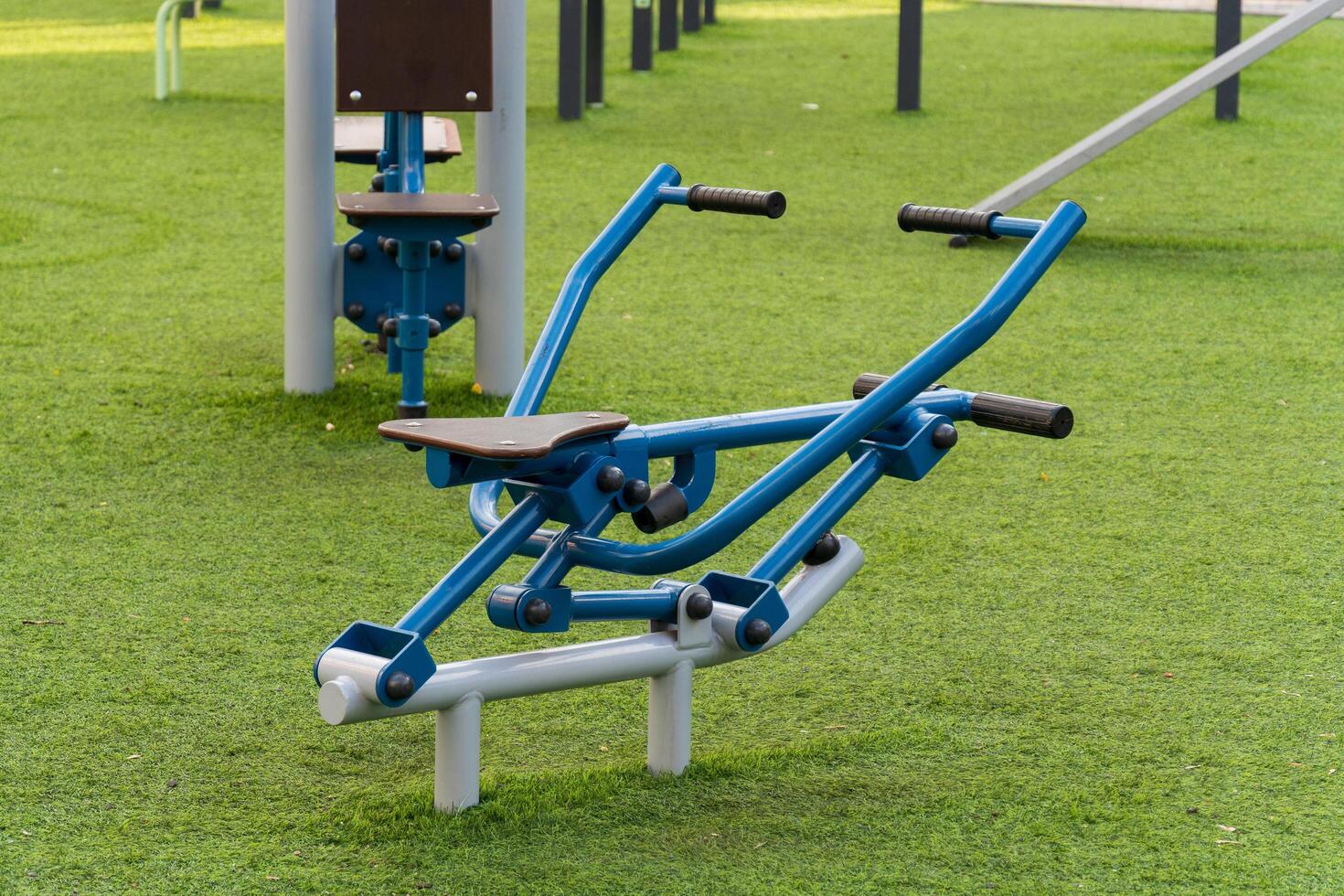 A dual-exercise machine sits on lush grass in a park, inviting users to engage in outdoor fitness training. This equipment supports healthy lifestyles and promotes active living photo