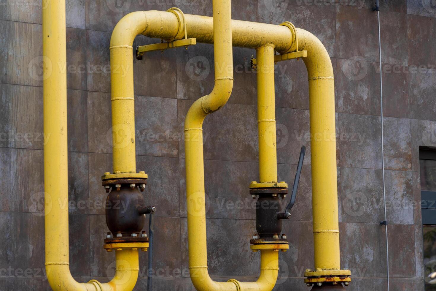 Yellow gas pipes are installed on a building's exterior, connecting energy sources effectively. The arrangement illustrates technology and infrastructure for fuel distribution in urban environments photo