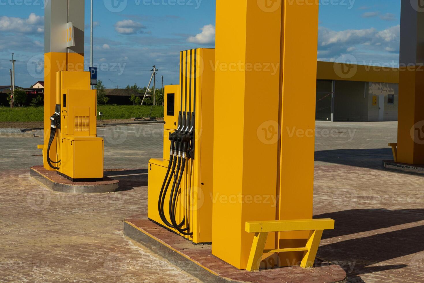 Bright yellow gasoline dispensers stand ready at a modern gas station. The setting is spacious with clear blue skies, showcasing an inviting atmosphere for vehicles needing fuel photo