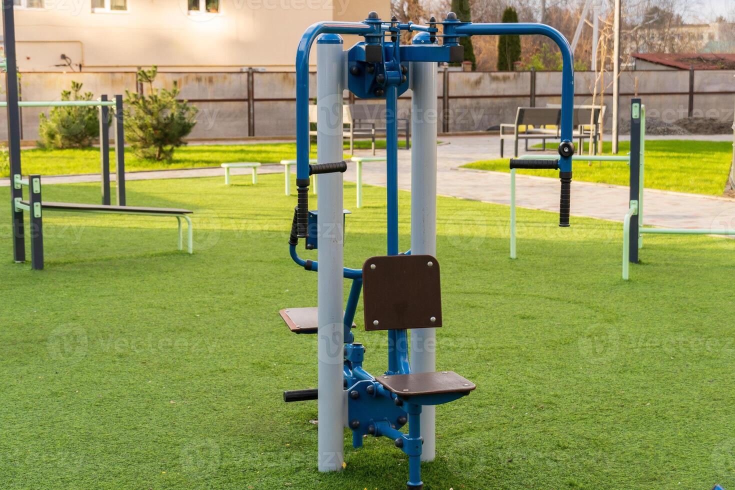 An outdoor gym machine designed for fitness training, situated on green grass in a public park. This equipment promotes healthy lifestyle choices and encourages community exercise routines photo