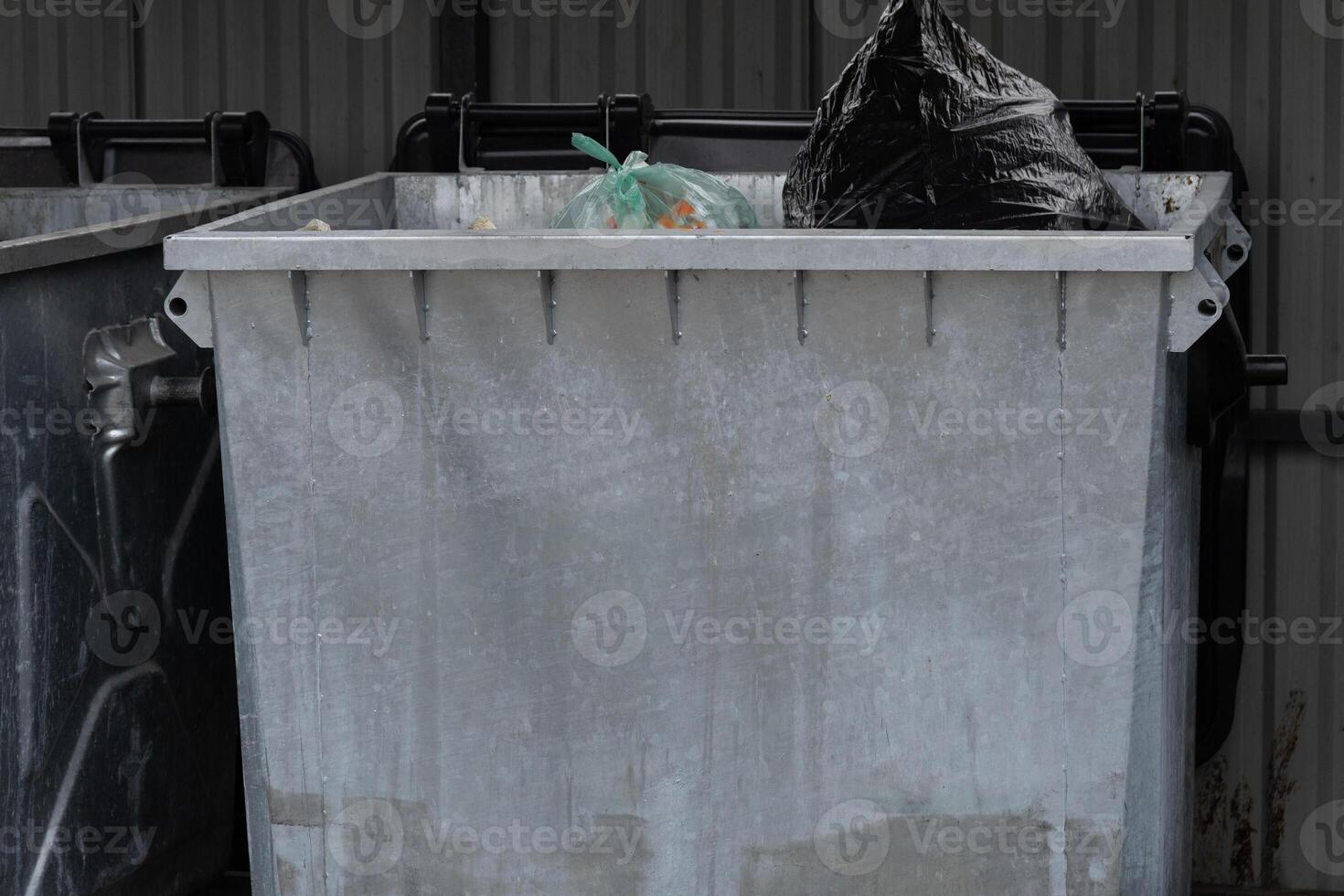 A metal garbage container overflowing with trash underscores the importance of waste management and recycling for promoting environmental sustainability in urban areas photo