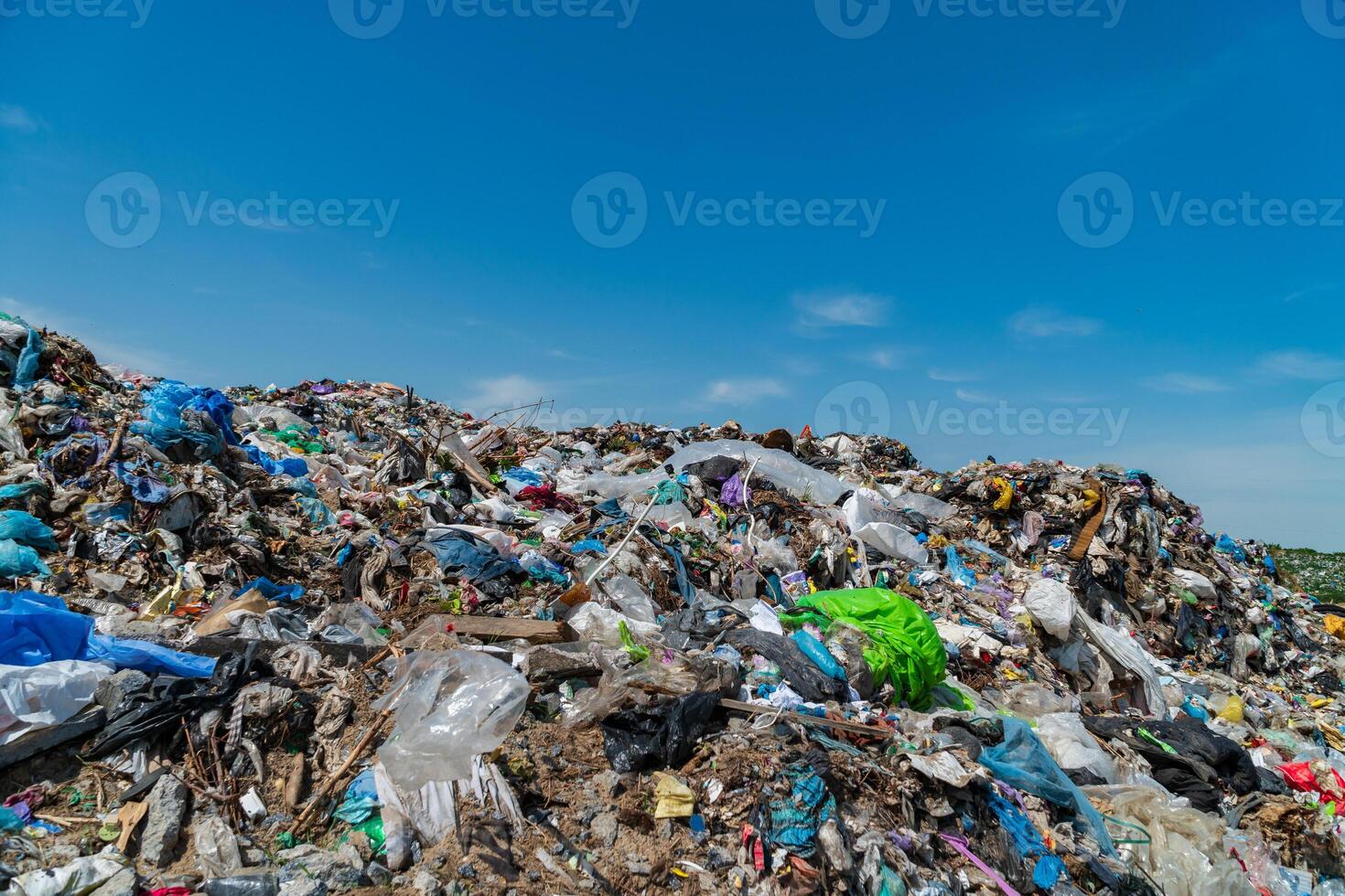A vast landfill overflowing with trash and plastic debris contrasts starkly against a bright blue sky, highlighting the critical issue of waste management and pollution affecting ecosystems photo