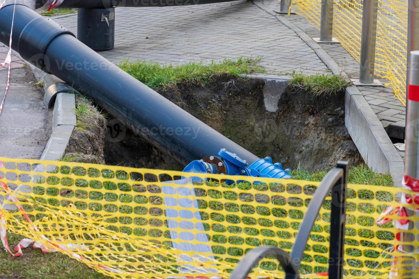Workers are engaged in replacing water pipes on the street, utilizing heavy machinery to dig and install new pipelines amidst construction hazards and safety barriers photo
