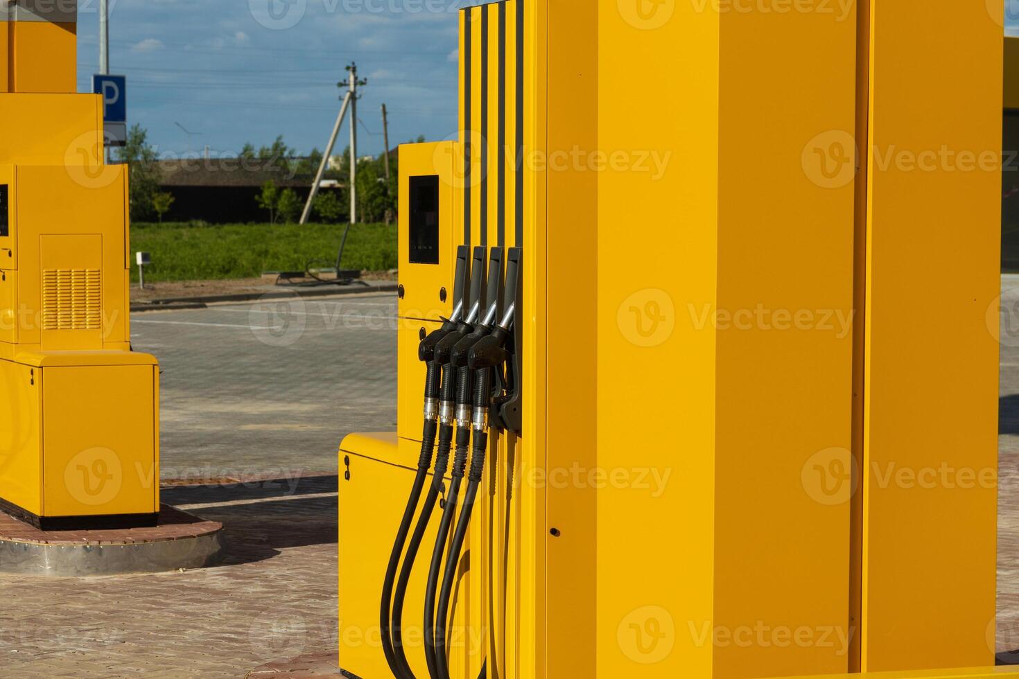 Bright yellow gas dispensers are prominently positioned at a fuel station, offering a convenient refueling option for vehicles on a clear day. The surroundings are open and spacious photo