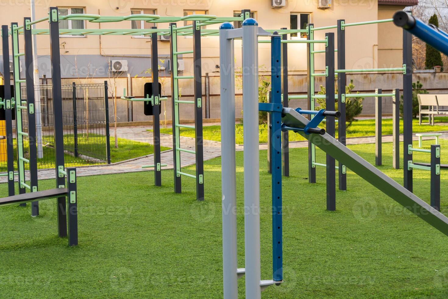 A variety of exercise machines are arranged in a green park, providing an inviting space for fitness training. The area is clean and designed for a healthy lifestyle photo
