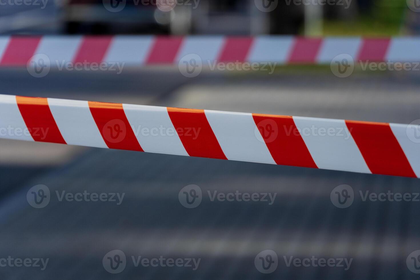 Caution tape in bright red and white stretches across a pathway in a city, signaling a warning and designating a forbidden area to ensure public safety and security photo
