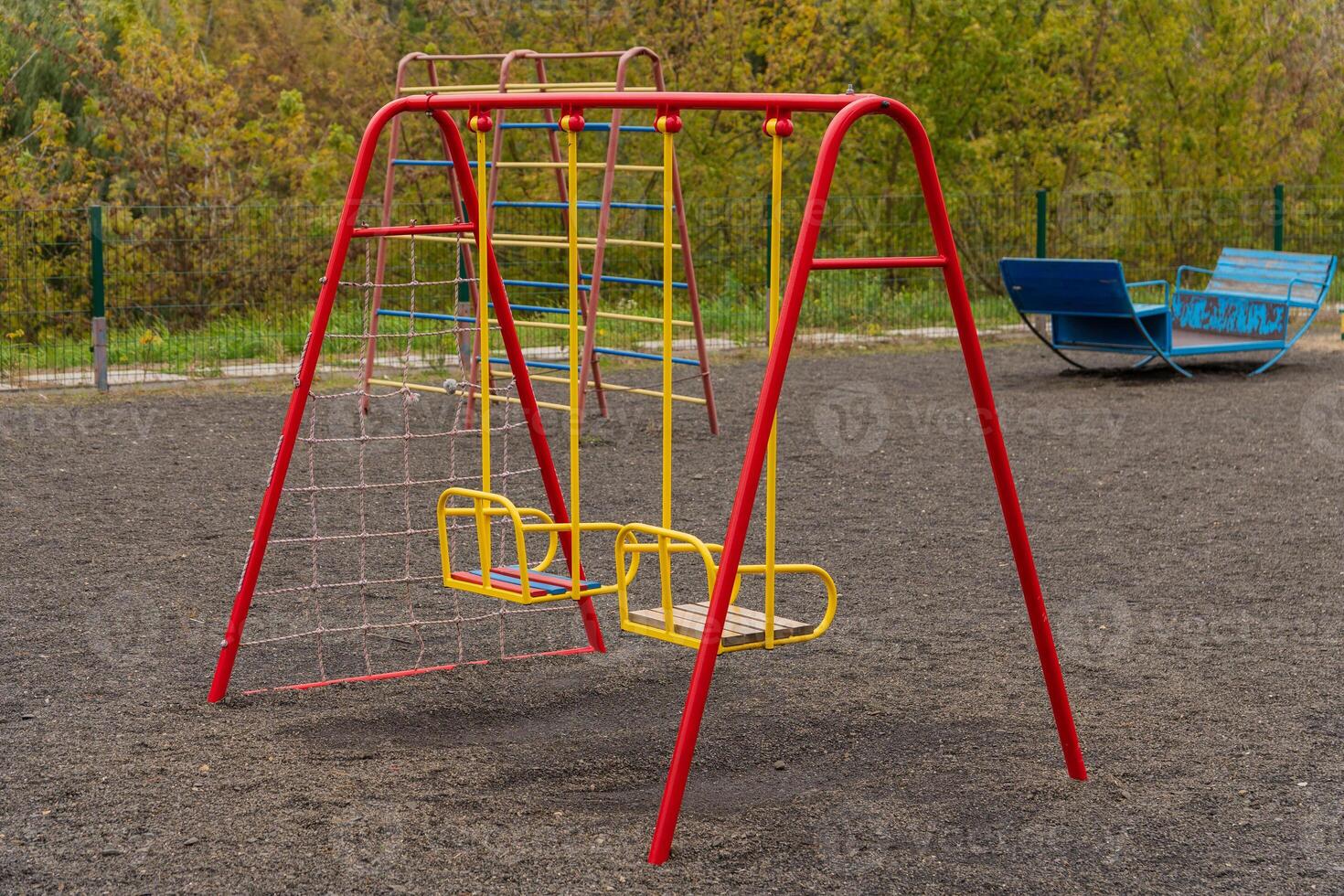 A vibrant swing set stands in a public park, surrounded by lush greenery. Children enjoy swinging back and forth, their laughter echoing as they play. The atmosphere is lively and cheerful photo