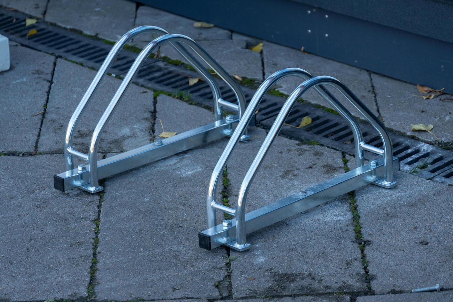 Sturdy and modern bicycle parking rack made of metal stands on a paved sidewalk, ready to support bikes for riders in a bustling urban environment photo