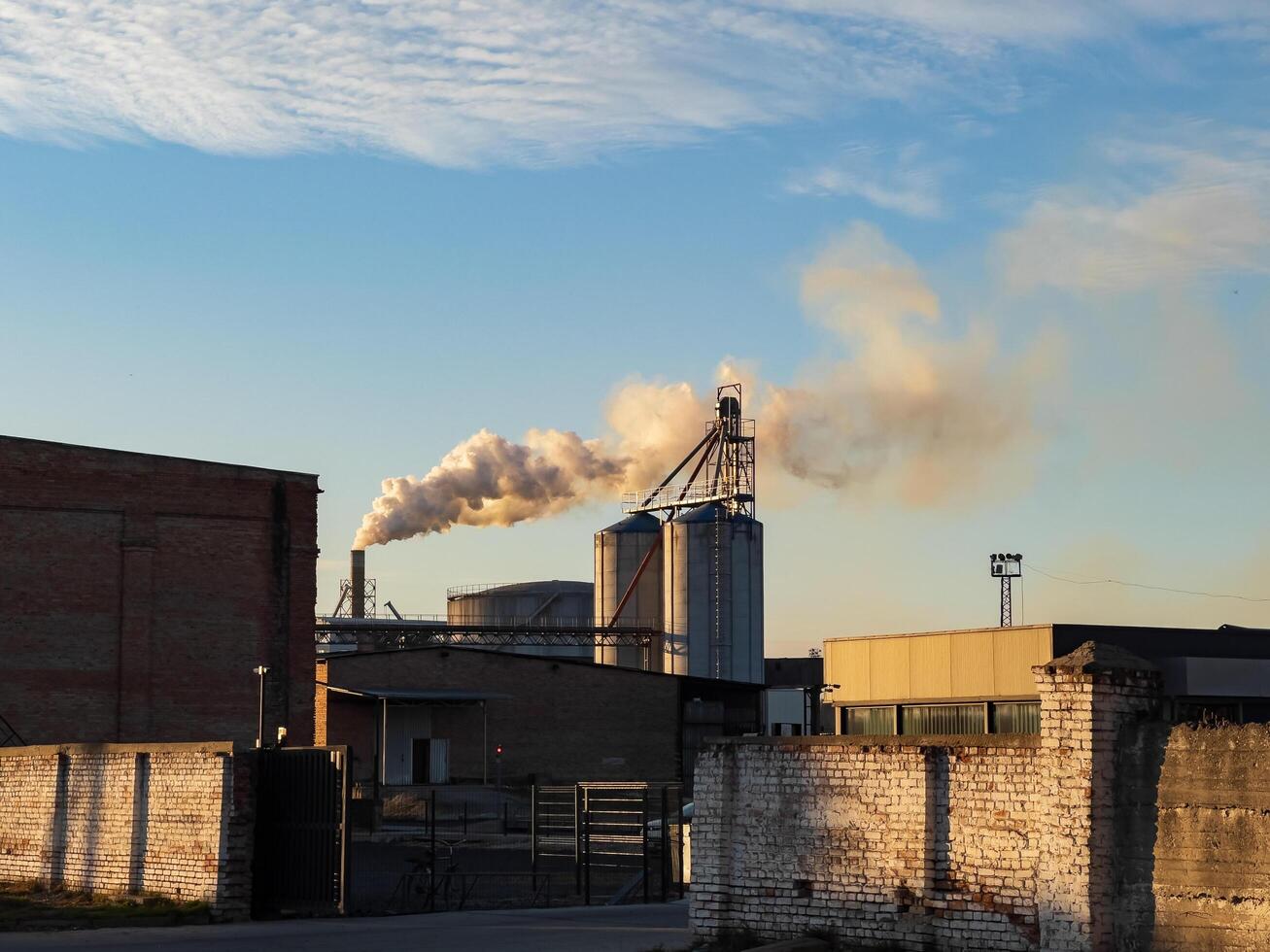 Against a vibrant twilight sky, smokestacks emit plumes of vapor from a manufacturing facility, showcasing the intersection of industry and nature during evening hours photo