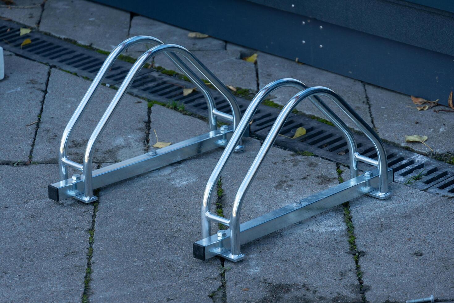 Two sleek metal bicycle racks stand on a paved surface, ready to provide secure parking for bicycles. The sleek design adds a modern touch to the urban environment photo