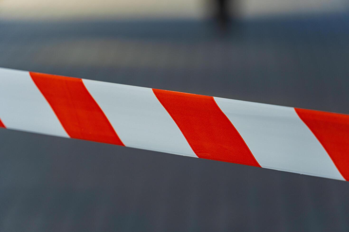 Vivid cautionary tape, featuring bold red and white stripes, signals a restricted area in a bustling city environment under bright daylight photo