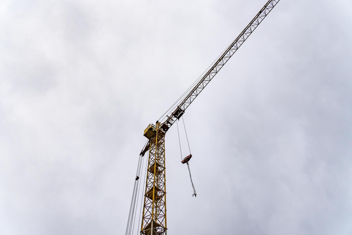 A towering yellow crane stands against an overcast sky, lifting heavy materials at a bustling construction site, symbolizing progress and ingenuity in urban development photo