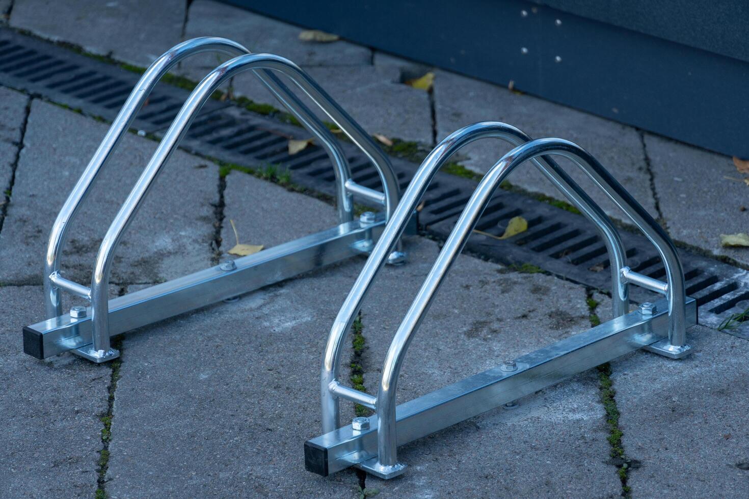 Two sleek, modern bicycle parking racks stand prominently on a sunlit pavement, encouraging cyclists to secure their bicycles while enjoying the city photo