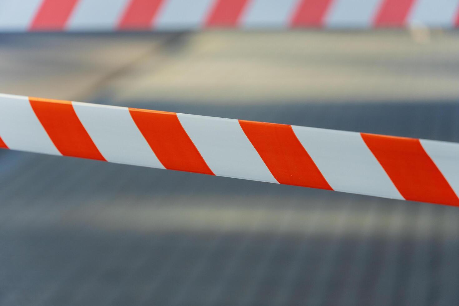 Bright orange and white striped barrier tape stretches across a walkway, while soft light illuminates the pavement, hinting at an active city in the morning photo