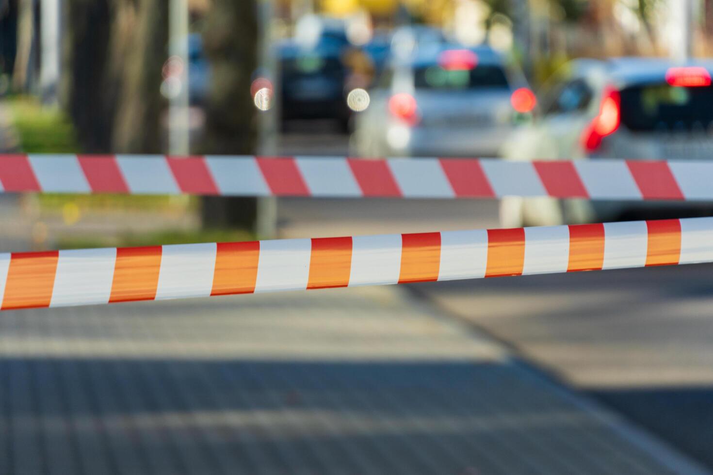 A vibrant barrier blocks traffic on a bustling city road, while cars line up in anticipation, highlighting the urban rush and everyday halt of movement photo
