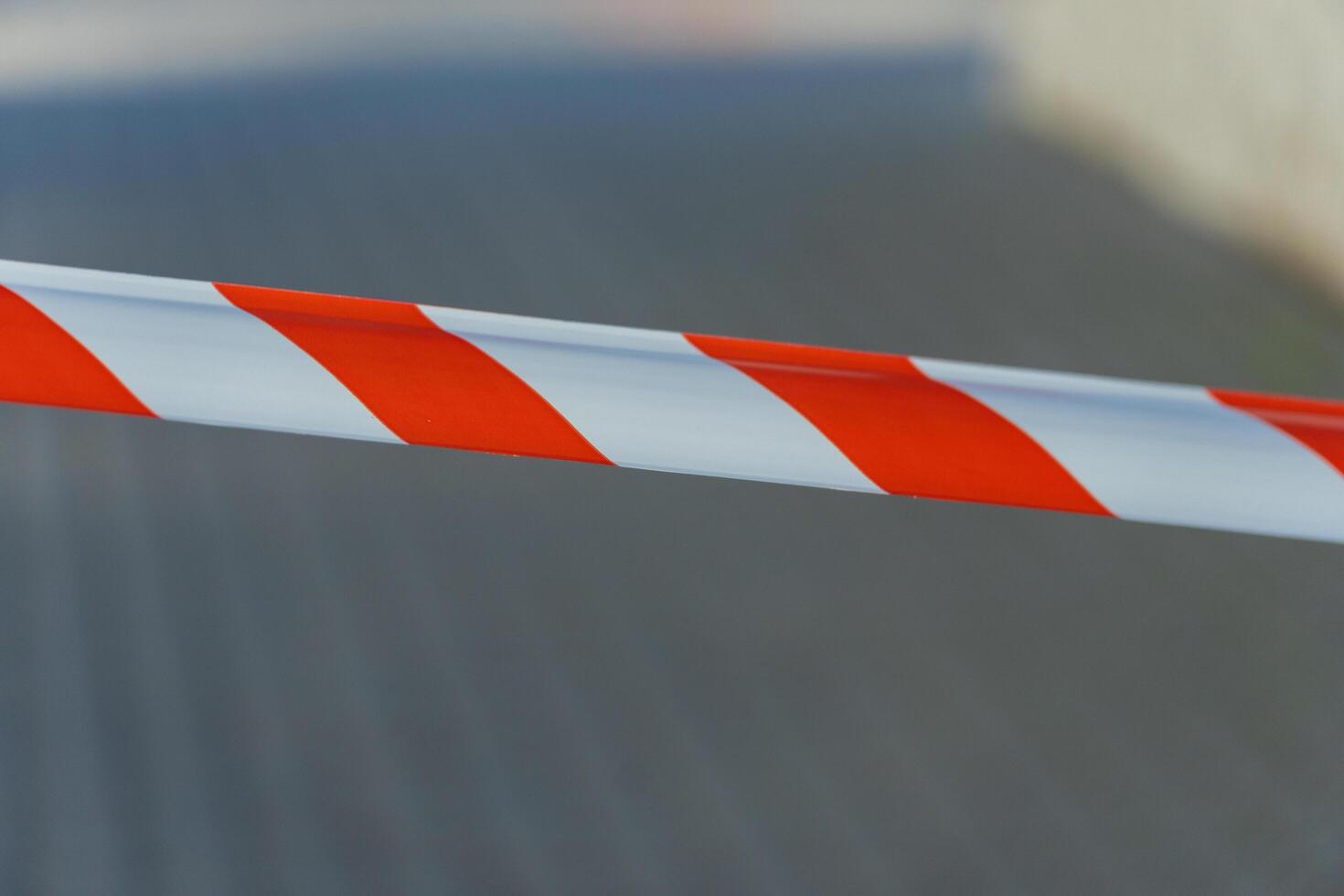 Brightly colored cautionary tape blocks access to a deserted pathway, highlighting a restricted area in an urban environment, illuminated by the midday sun photo