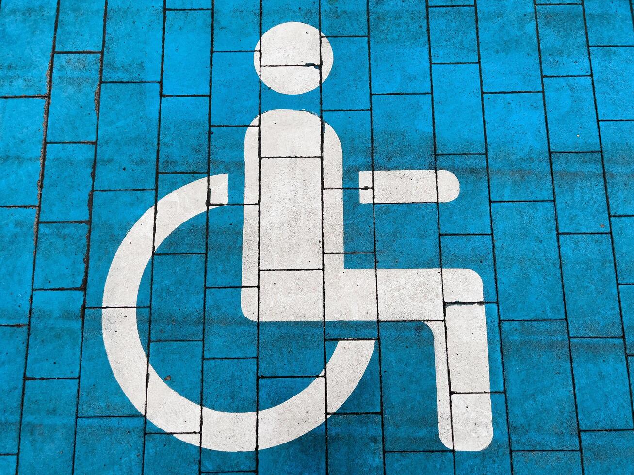 Bright blue pavement displays a clear accessibility symbol, promoting inclusivity in urban environments. This inviting marking encourages awareness and support for individuals with disabilities photo