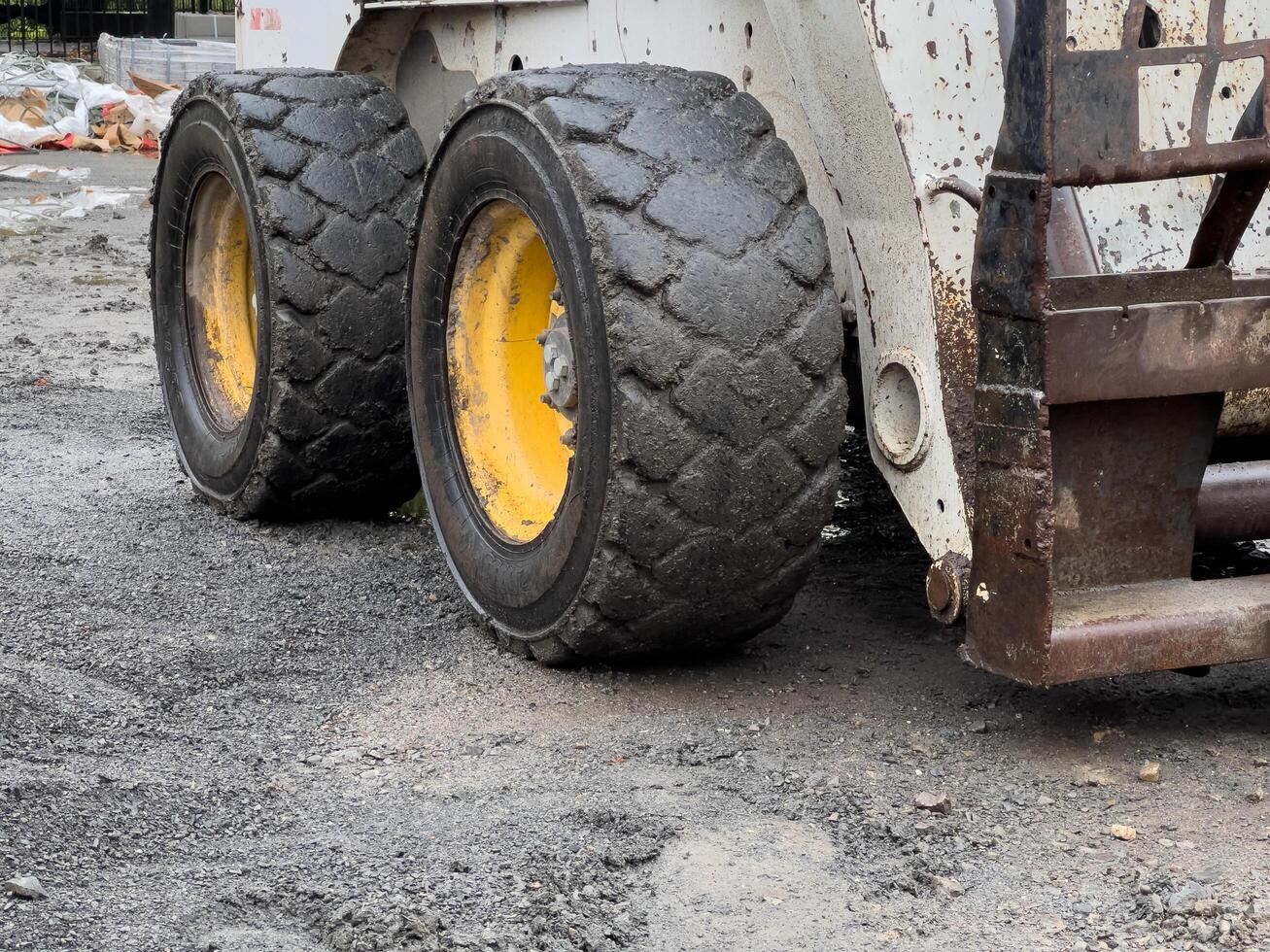 These rugged tires, caked in dirt and gravel, belong to a construction vehicle parked in a bustling urban area undergoing revitalization, showcasing the blend of grit and progress photo