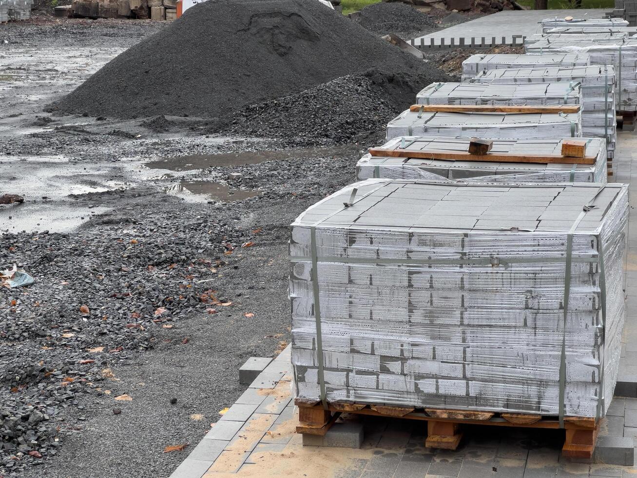 Crates stacked high with gray concrete blocks are neatly arranged on pallets, ready for use in construction at a bustling site in the early hours of the day photo