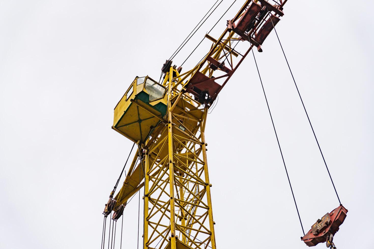The bright yellow crane dominates the skyline, its operator carefully maneuvering materials for an ongoing construction project as clouds roll by above photo