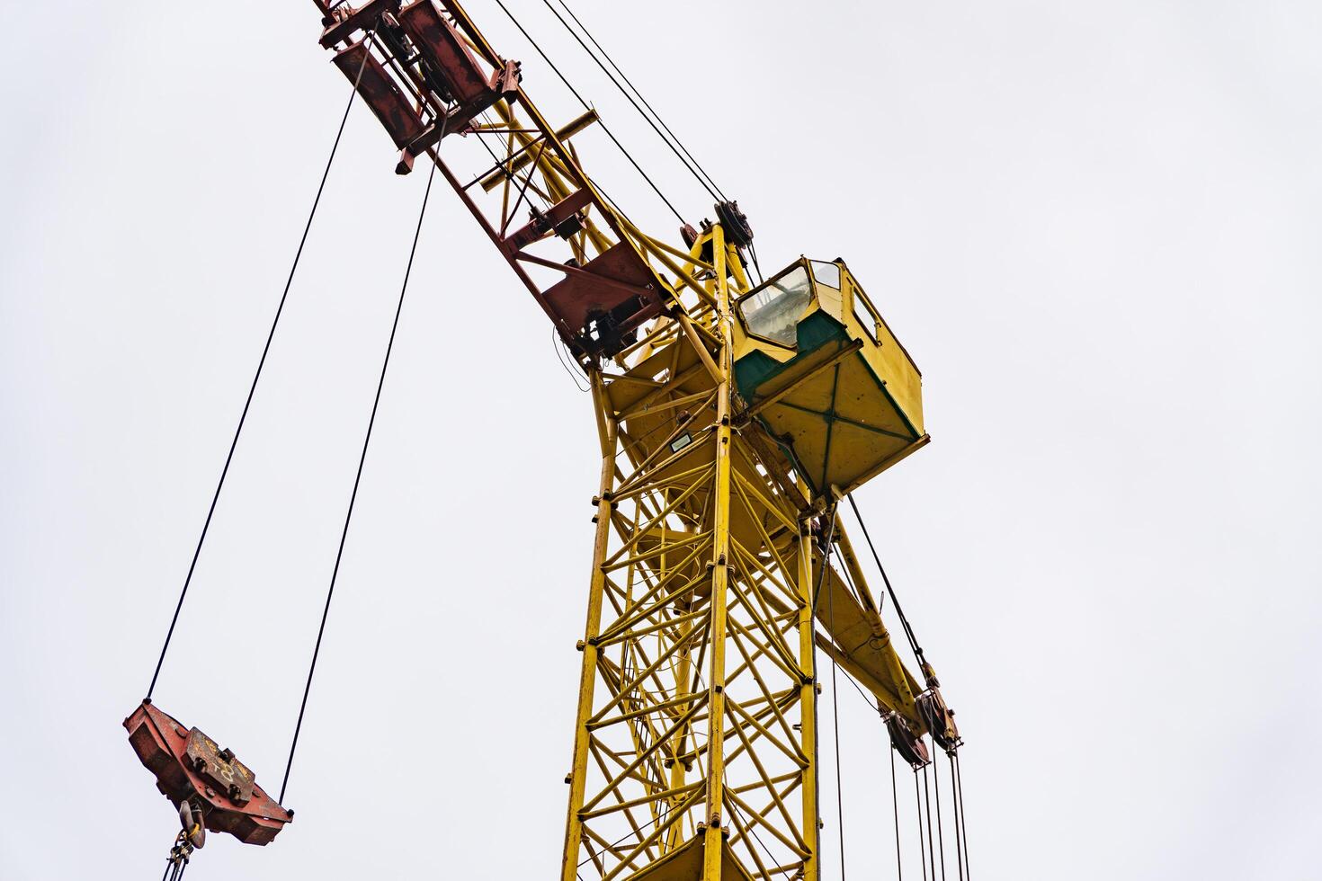 A tall yellow construction crane reaches skyward, its sturdy frame standing out against the overcast sky, showcasing the strength of modern engineering in urban development photo