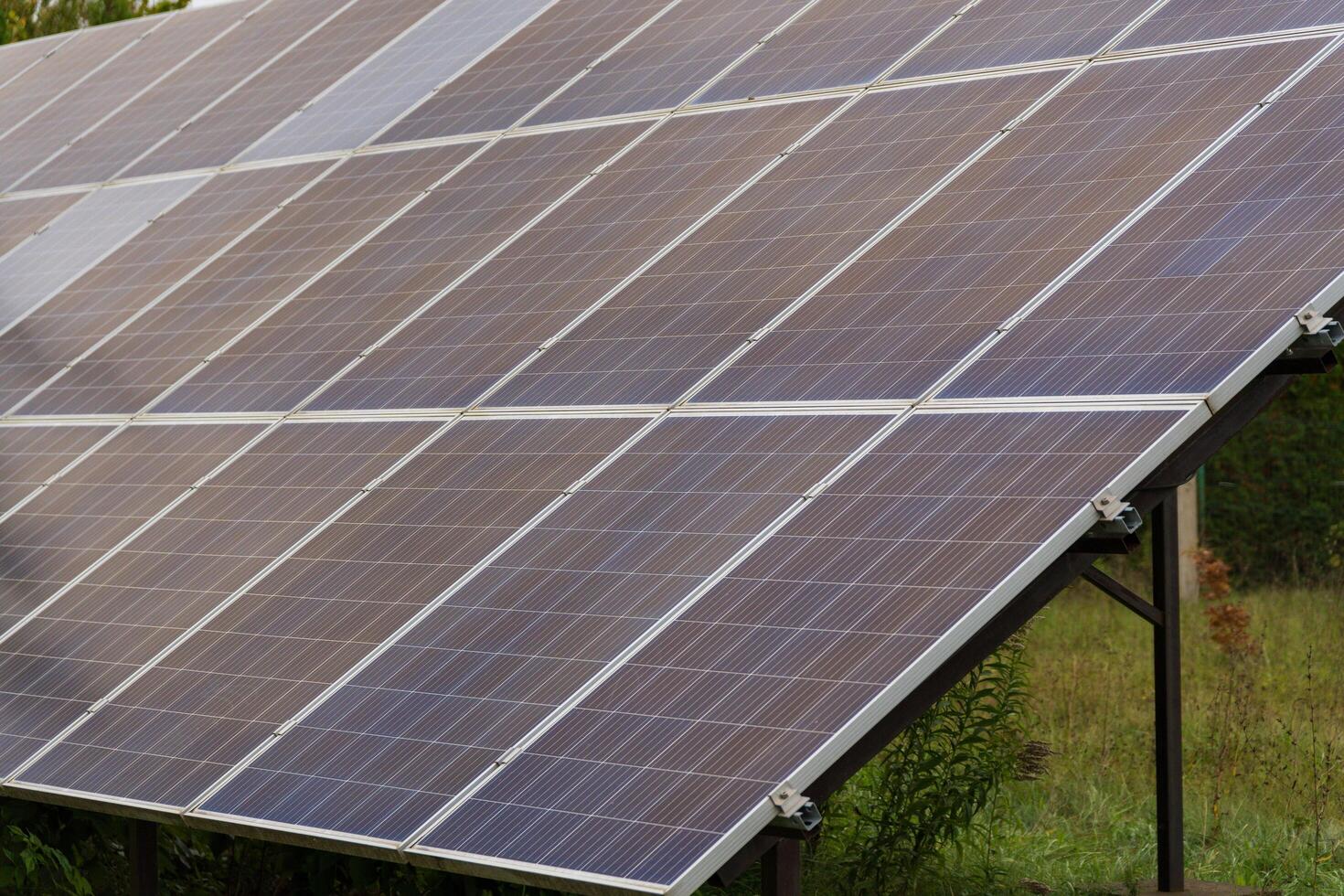 Rows of solar panels glisten in the afternoon light, reflecting the vibrant green surroundings. This clean energy initiative showcases a commitment to sustainability and innovation in technology photo
