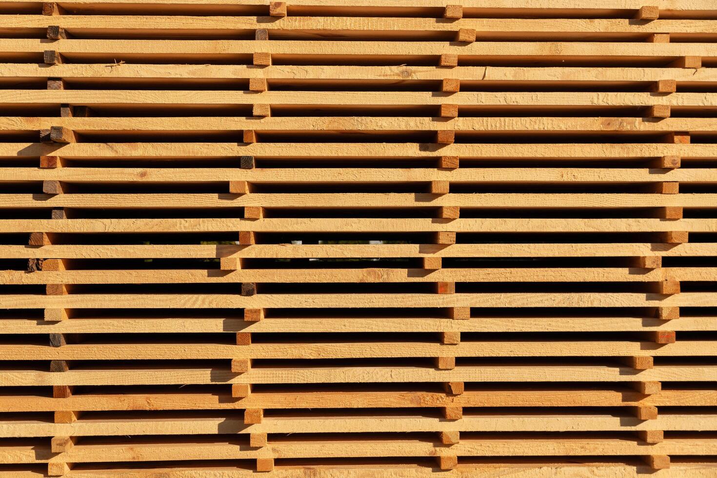 Sunlight casts intricate shadows as wooden slats form a striking pattern, showcasing the beauty of natural materials in an outdoor setting photo