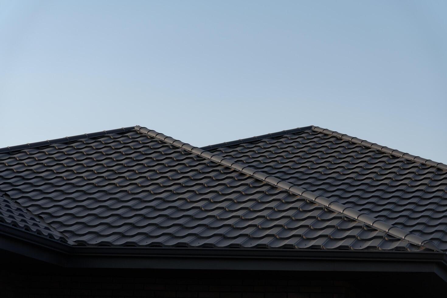 The structure showcases a contemporary metal tile roof with a wave pattern, set against a bright blue sky. This roofing choice enhances the home's aesthetic appeal and durability photo