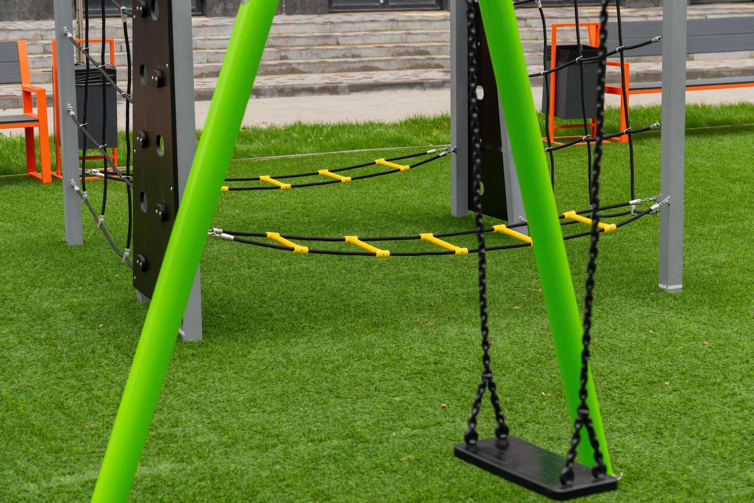 Children enjoy swinging on a brightly colored playground swing set, surrounded by lush green grass, inviting play and exploration during a sunny day photo