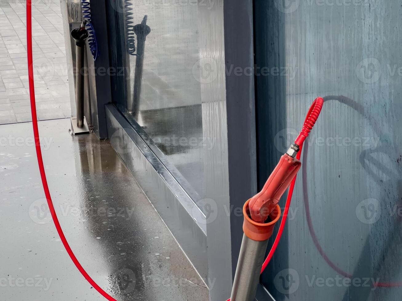 A high-pressure washing setup is in use at an outdoor service station, efficiently cleaning vehicles with powerful jets of water on a cloudy day photo