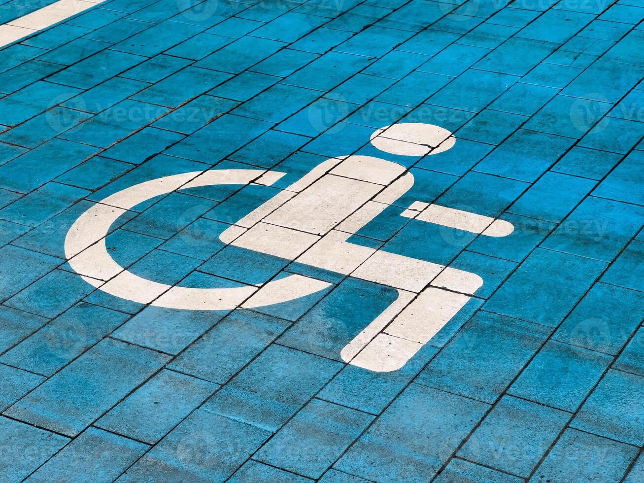 A designated parking spot reserved for disabled individuals features a bright blue paving and a clear accessibility symbol painted in white. This ensures easy identification and access photo
