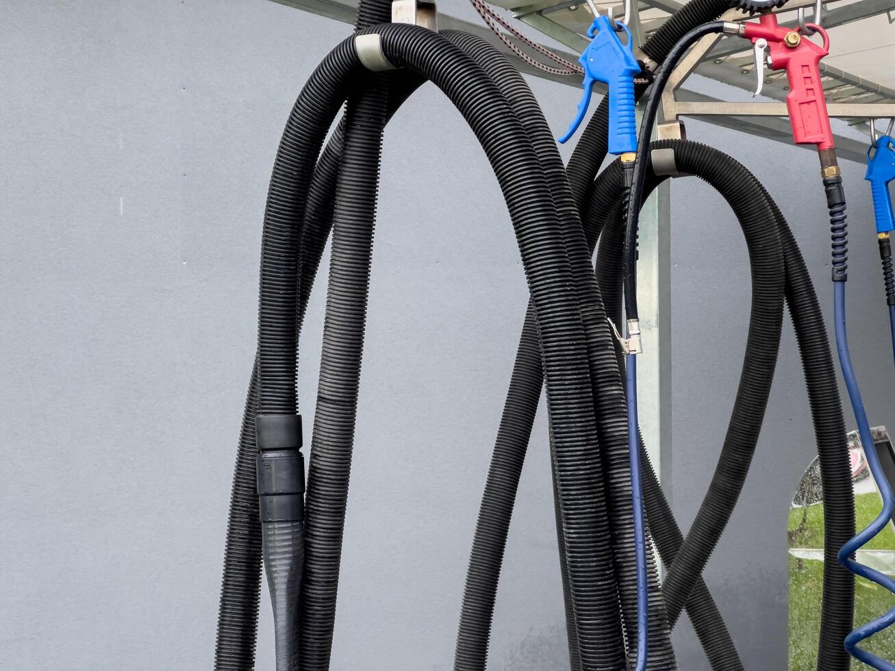 High pressure car washer guns and hoses are neatly organized at a car wash station, ready for use during busy service hours, ensuring efficient cleaning photo