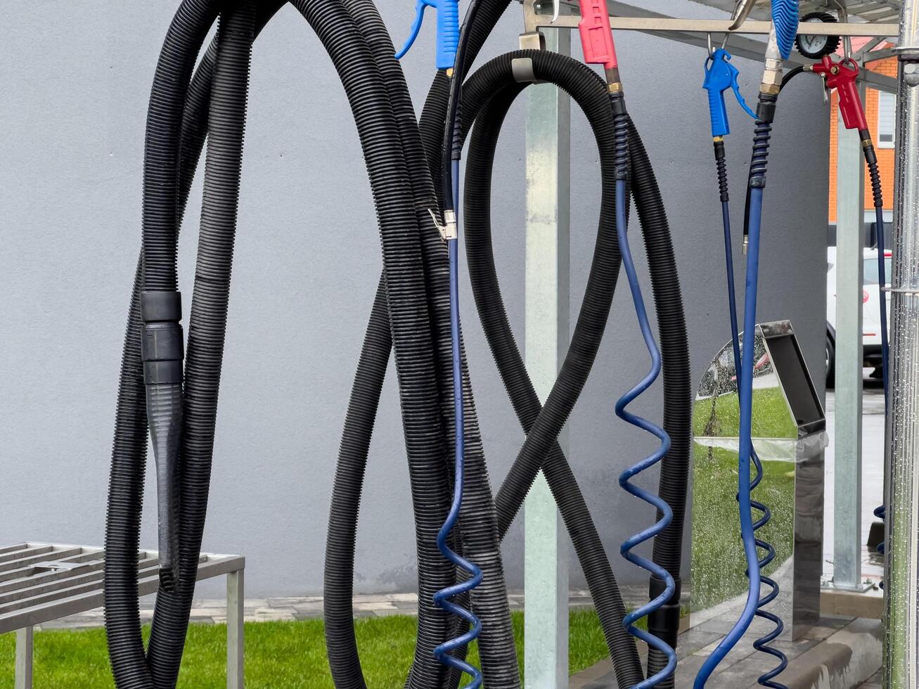 High pressure car washer guns and hoses are neatly arranged at a car wash station, ready for use by staff as vehicles arrive for cleaning photo
