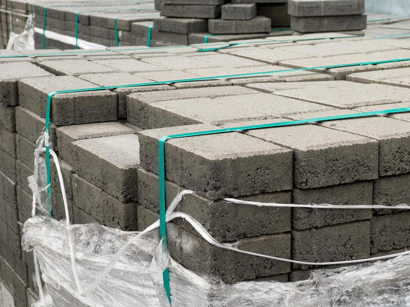 Cobblestones are neatly stacked and secured with straps, ready for a construction project. The site showcases organized materials essential for paving tasks photo