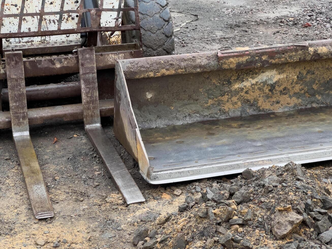 A compact loader equipped with a bucket attachment rests on a construction site, surrounded by dirt and rocks, awaiting the next earthmoving job photo