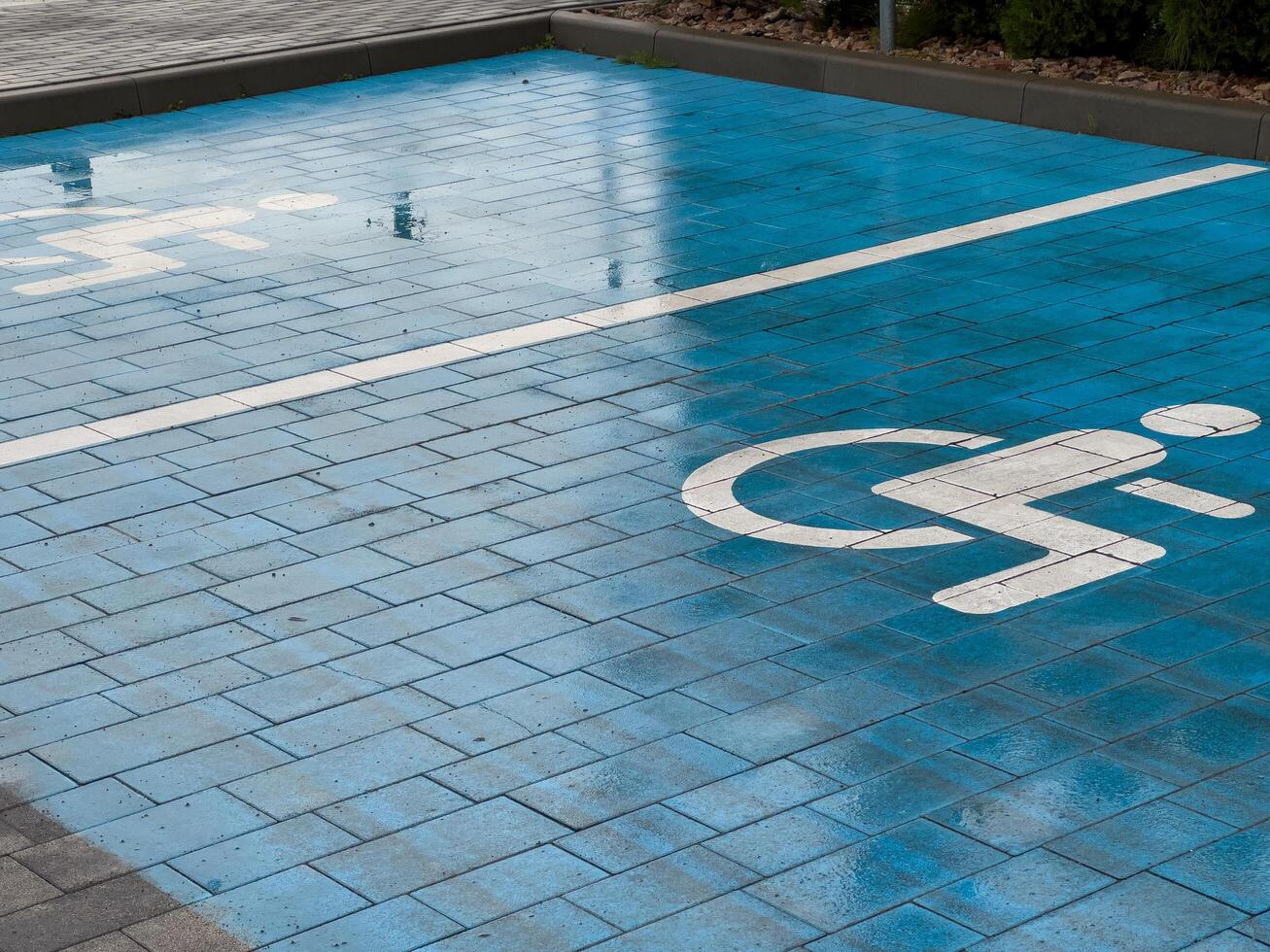 A blue pavement section is marked with a symbol indicating a designated parking spot for disabled individuals, highlighting accessibility in the area photo